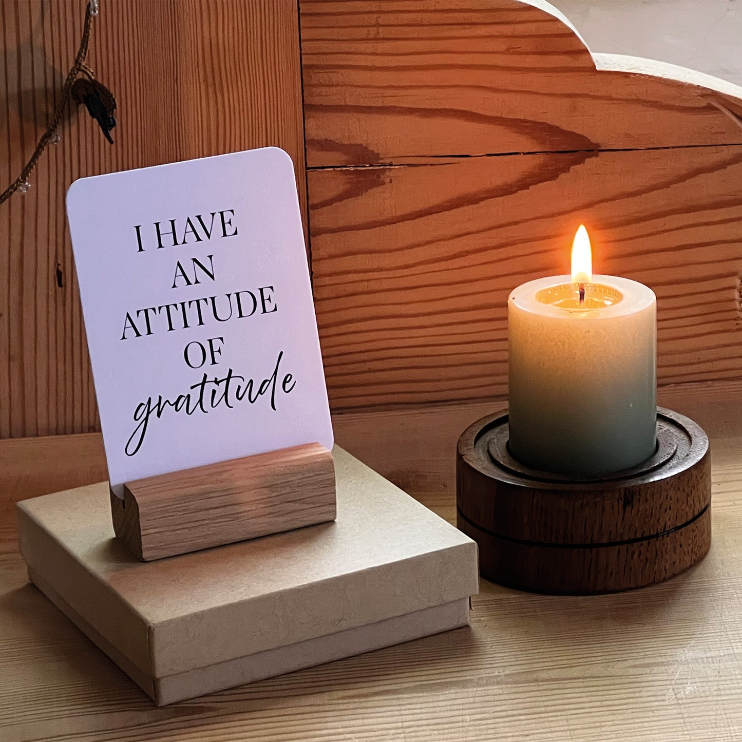 Daily Affirmation Card displayed in a handmade oak stand with the "I have an attitude of gratitude" affirmation alongside a candle and presentation gift box from the Daily Affirmation Cards – Reflections collection